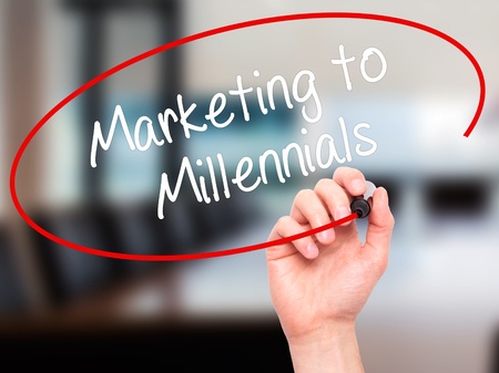 man hand writing marketing to millennials with black marker on visual screen. isolated on background. business, technology, internet concept. stock photo
